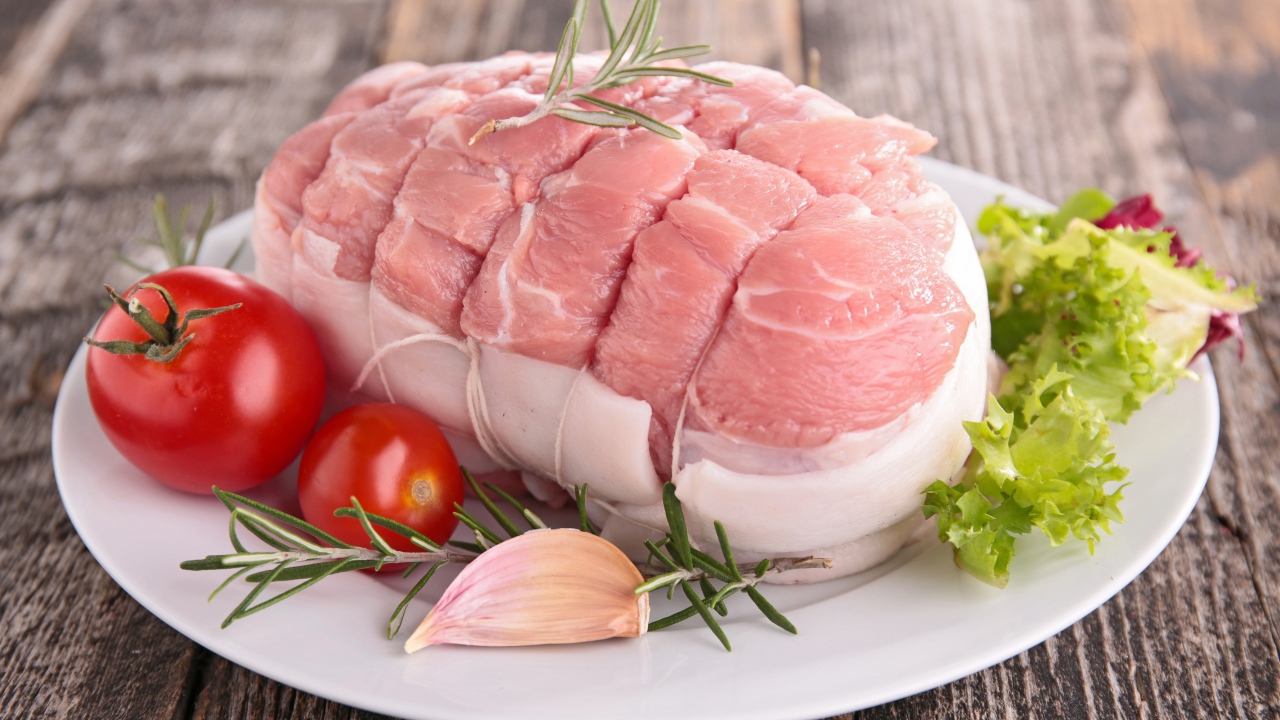 Кусок свежего мяса со свежими помидорами, чесноком и листьями салата