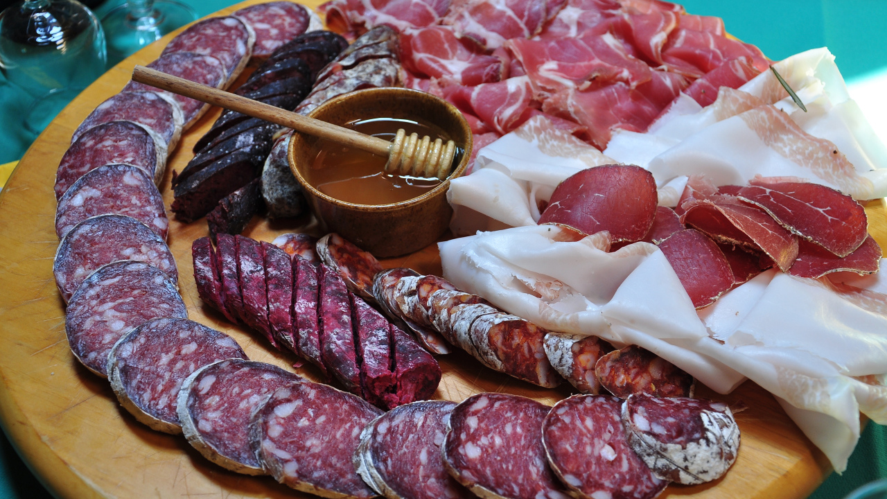 Аппетитная мясная нарезка на разделочной доске с медом