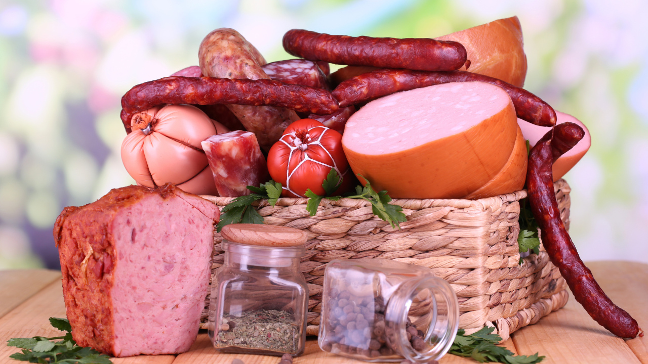 Аппетитная колбаса в корзине на столе со специями