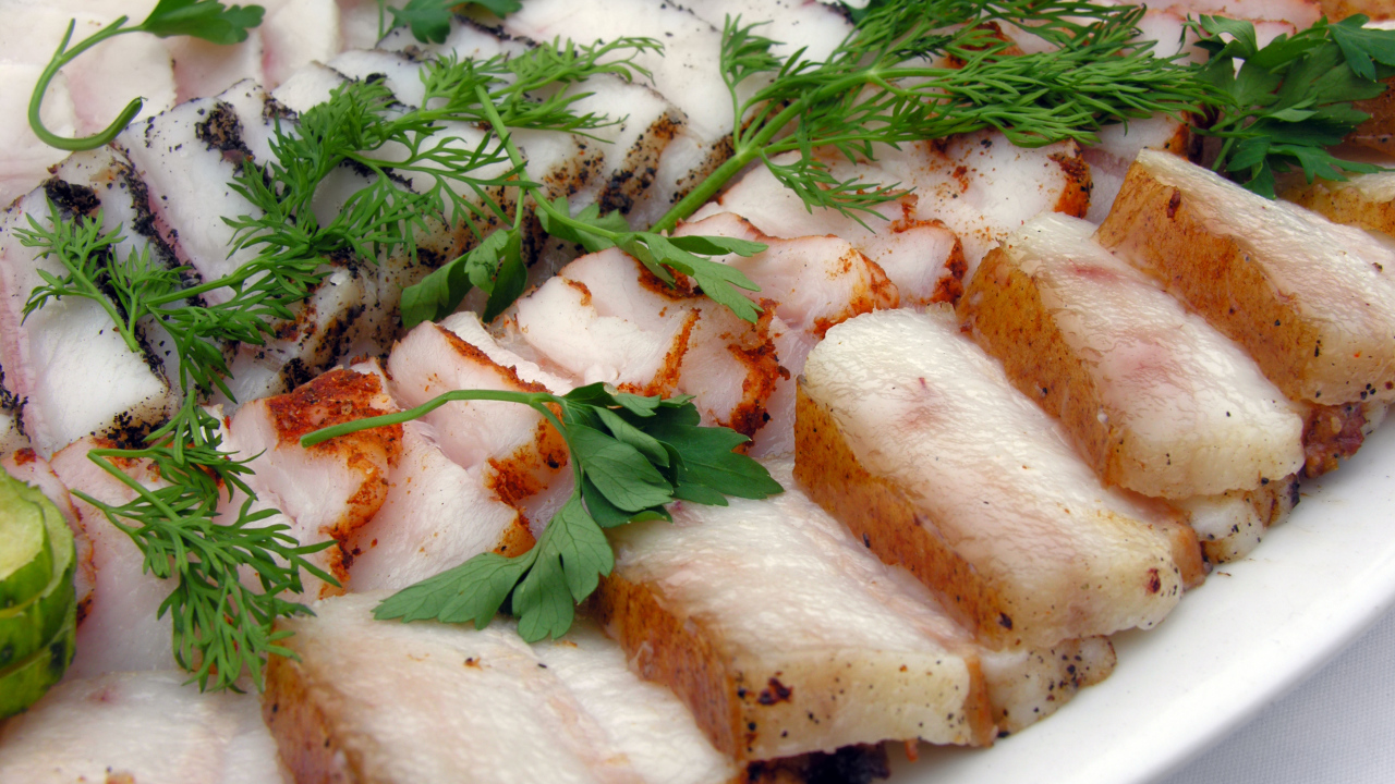 Аппетитное нарезанное копченое сало с зеленью 