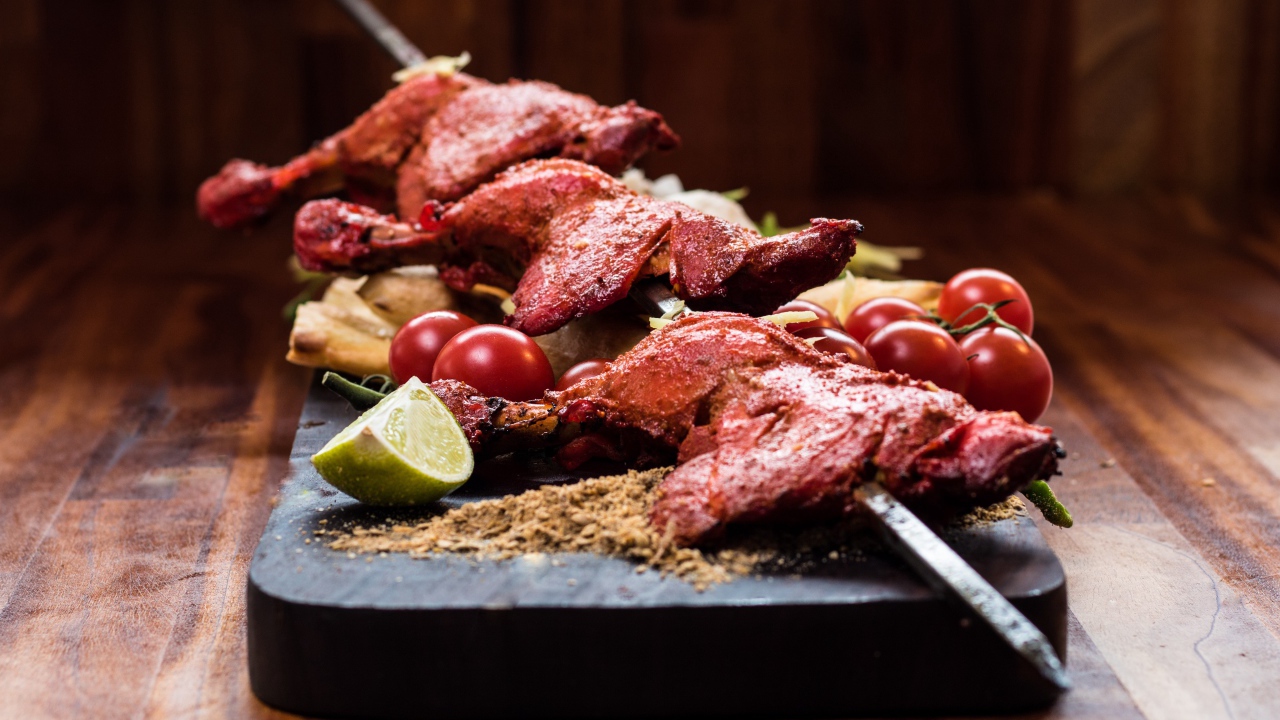 Курица жареная на шампурах на столе с овощами 