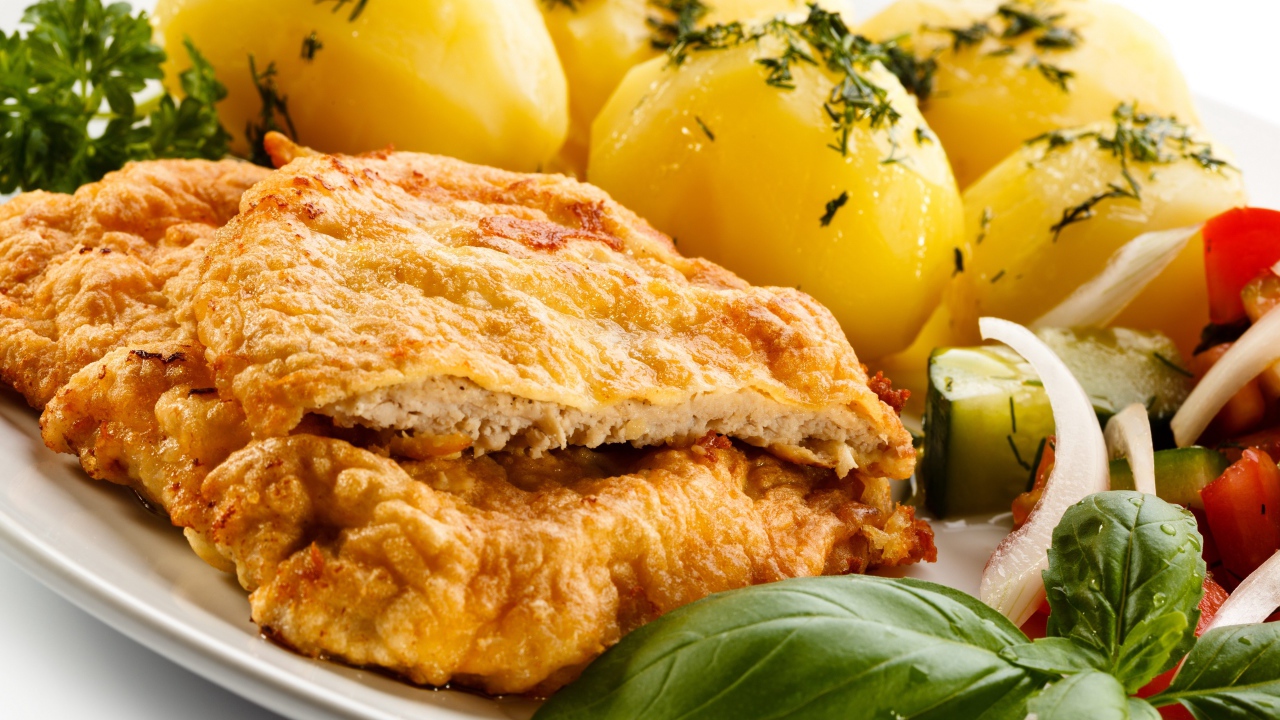 Отбивная на тарелке с вареным картофелем и салатом