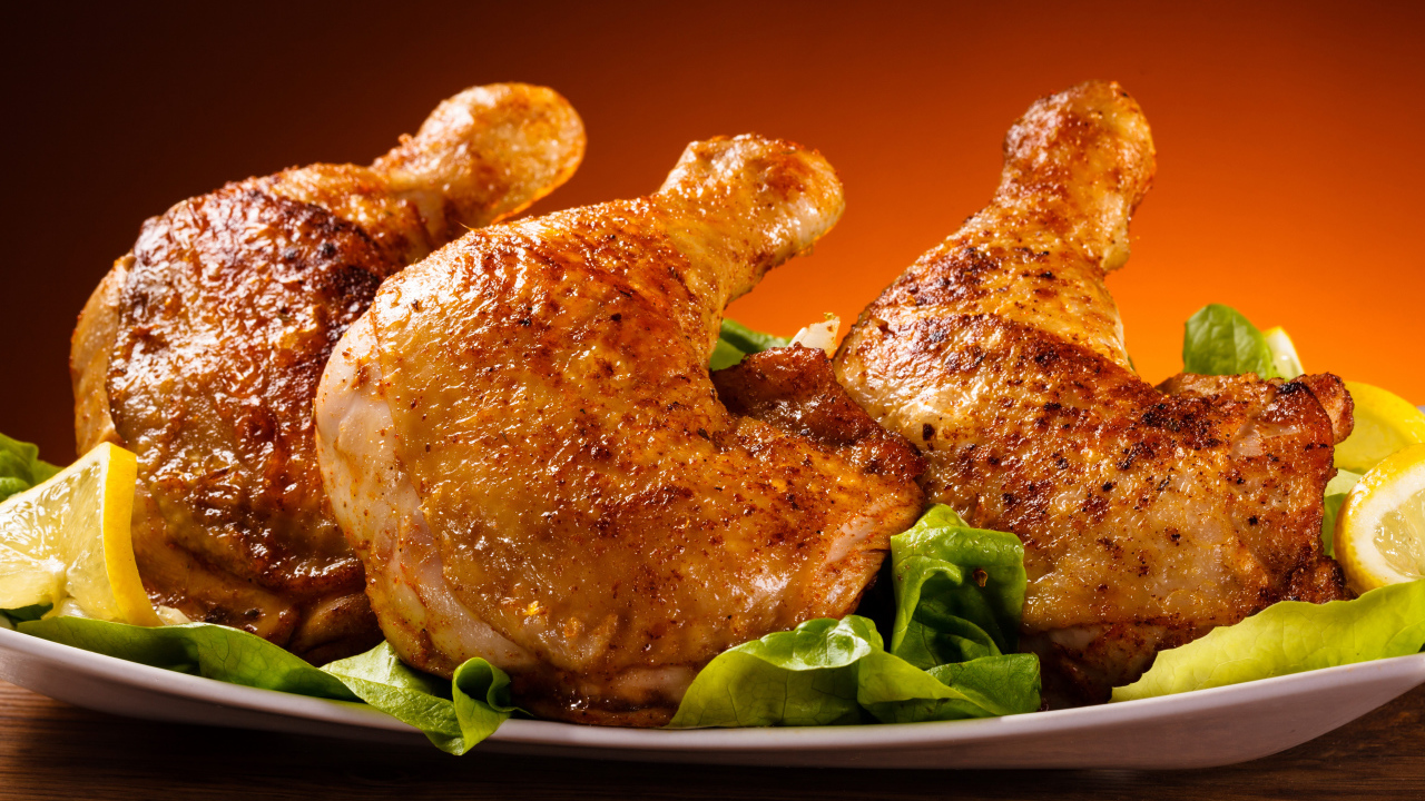 Жареные куриные окорочка на зеленых листьях салата 