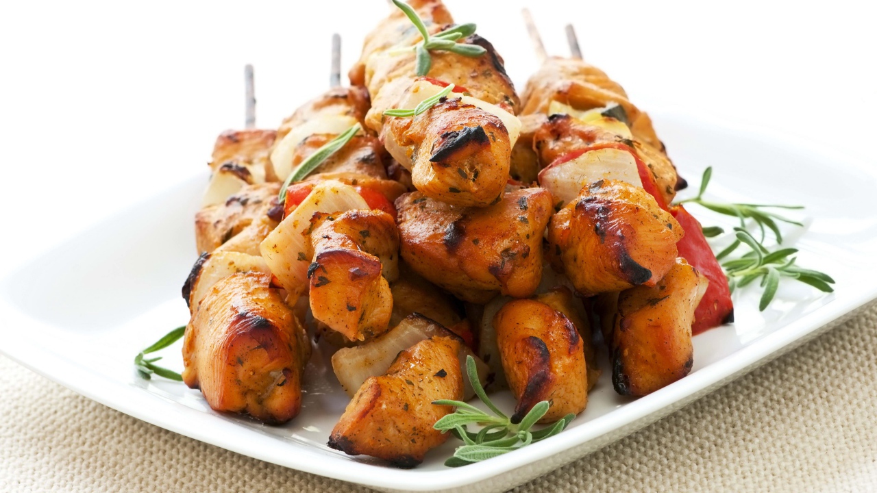 Шашлыки на белой тарелке с зеленью розмарина