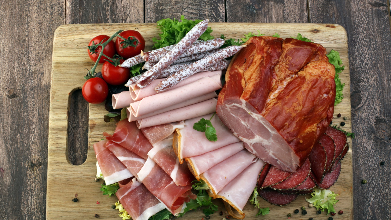 Мясная нарезка на разделочной доске с помидорами