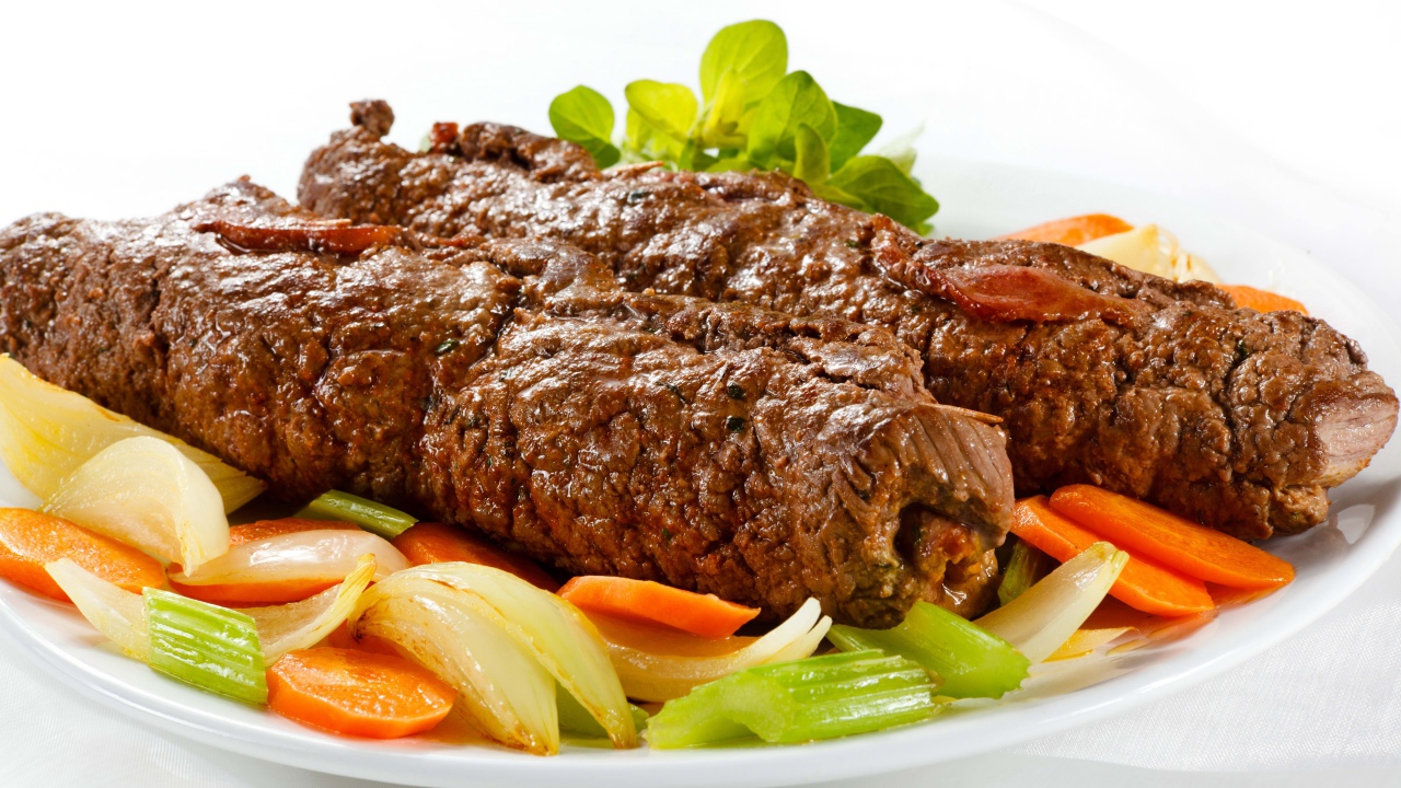 Свинина на тарелке с овощами на белом фоне