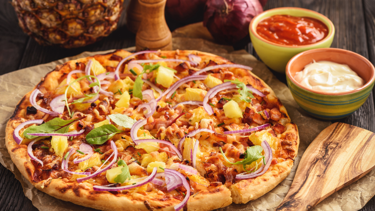 Пицца с ананасами и луком на столе с соусом