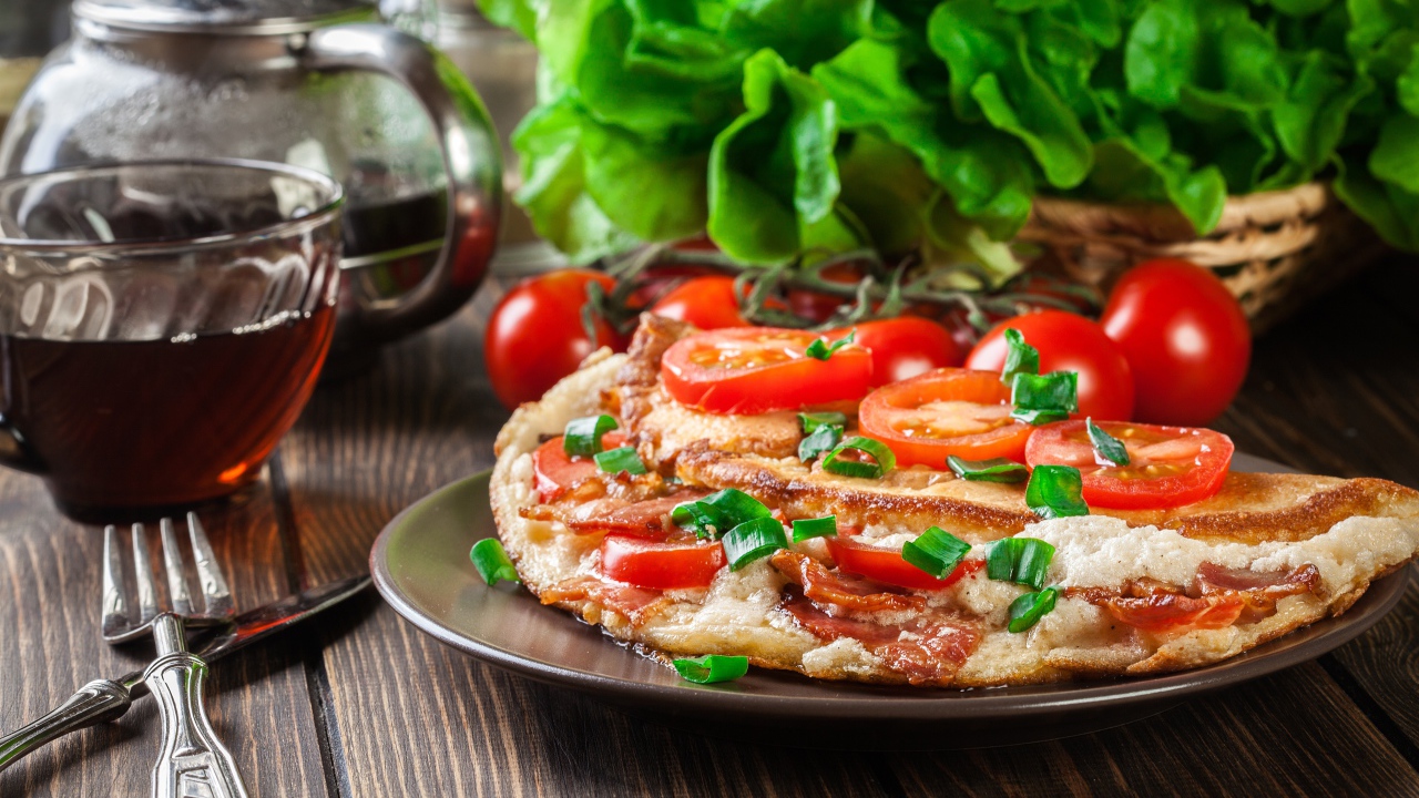 Пицца с помидорами на столе с чаем и зеленью 