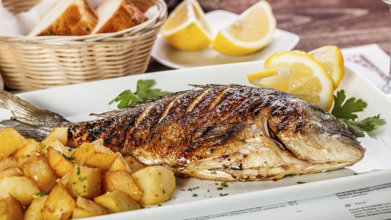 Запеченная рыба на тарелке с картофелем и лимоном 