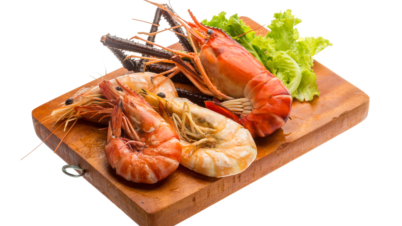 Вареные креветки с листьями салата на разделочной доске