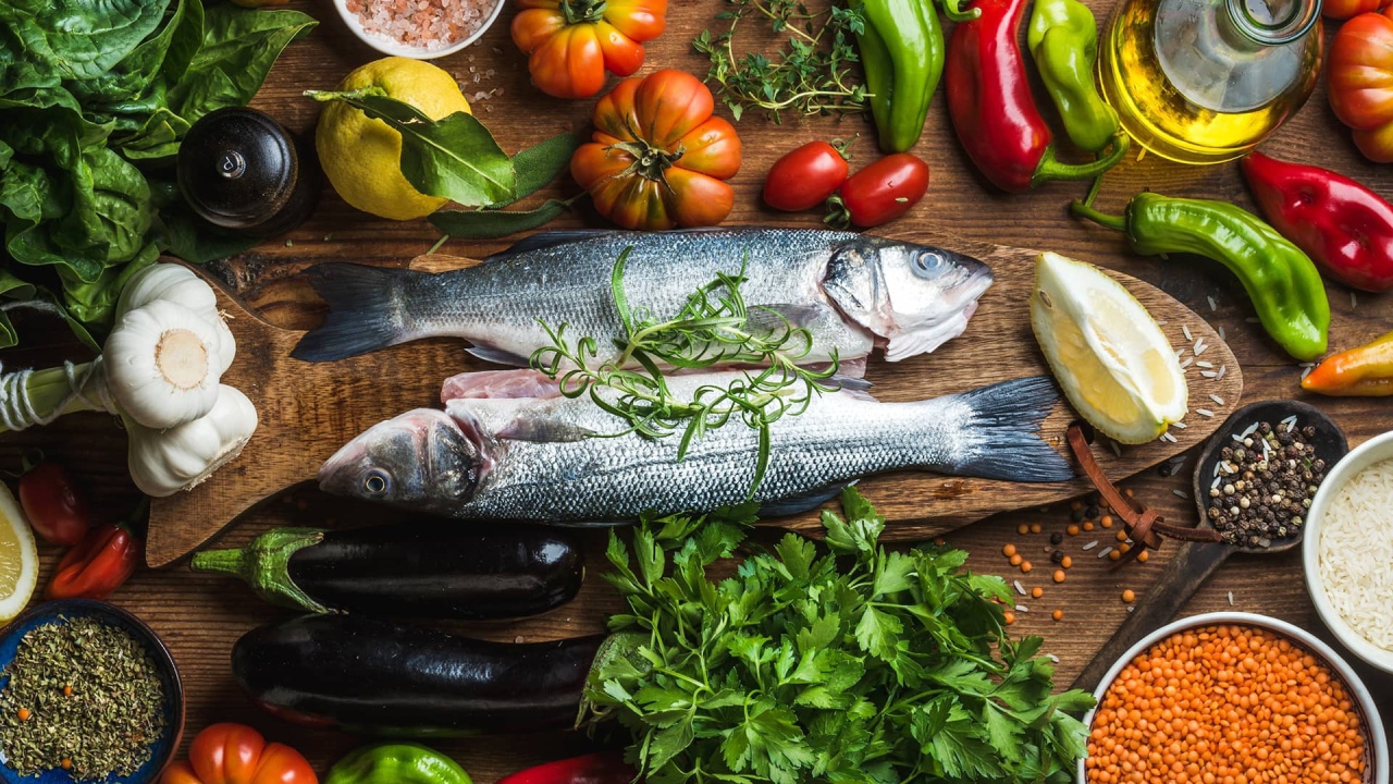 Свежая рыба на столе с овощами и зеленью 