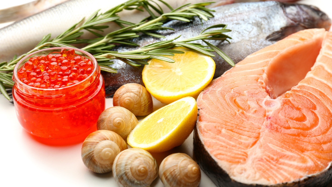 Red fish with snails and red caviar on a table with lemon and basil