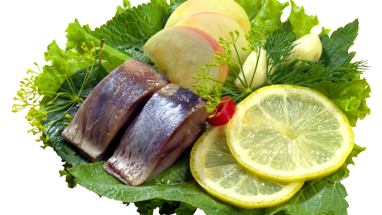 Кусочки сельди с кусочками яблока и лимона на белом фоне