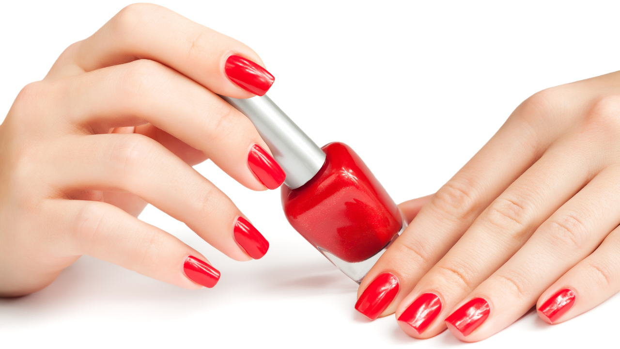 Женские руки с красным маникюром и лаком на белом фоне