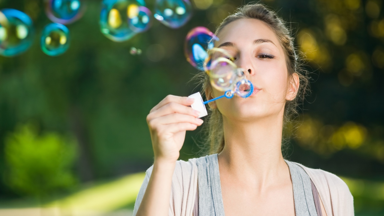 Милая молодая девушка пускает мыльные пузыри