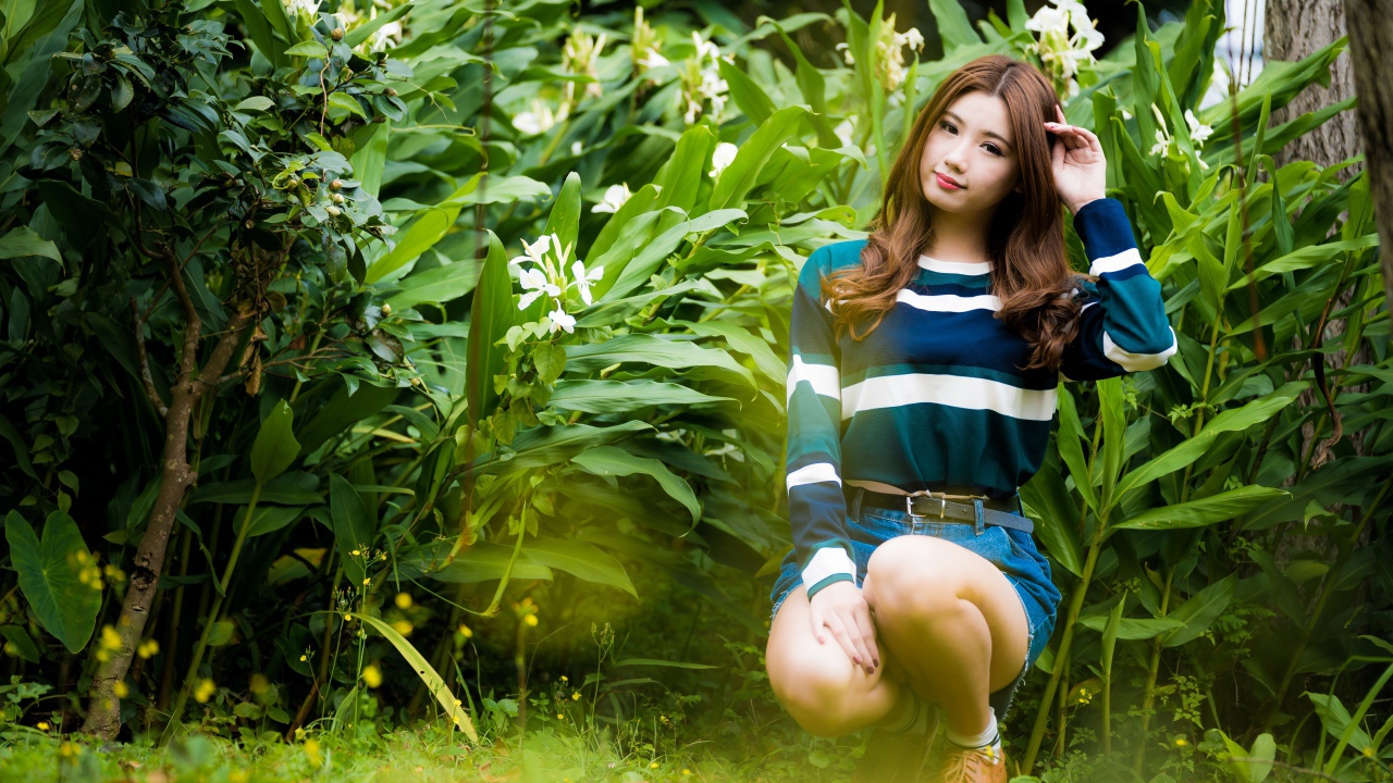 Молодая азиатка сидит в зеленых листьях 