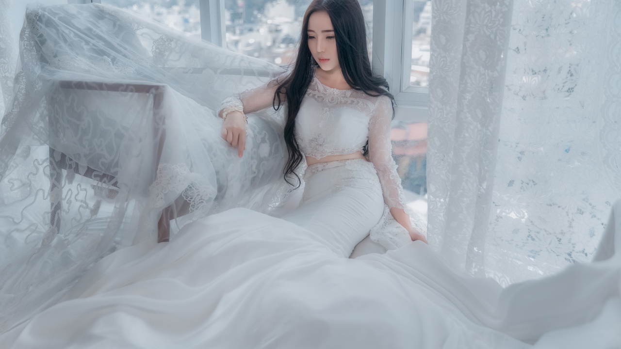 Красивая азиатка в белом свадебном платье сидит на полу