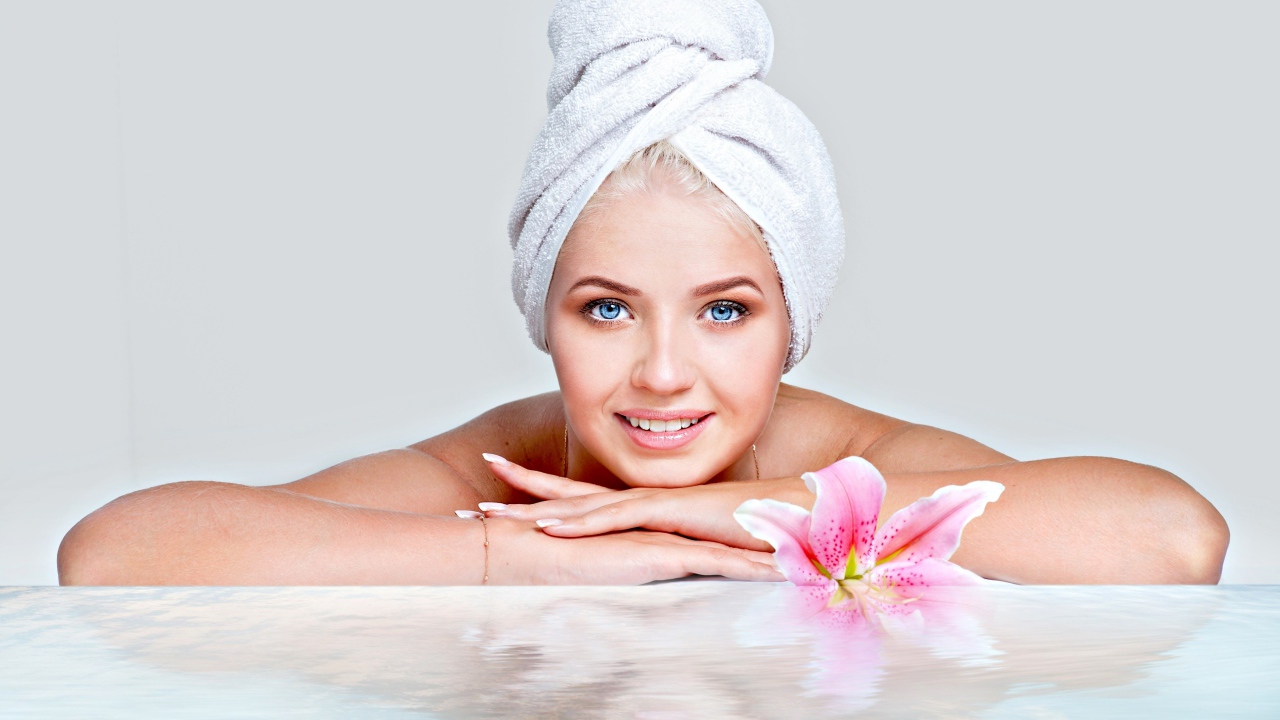 Красивая голубоглазая женщина в тюрбане с полотенца расслабляется в SPA