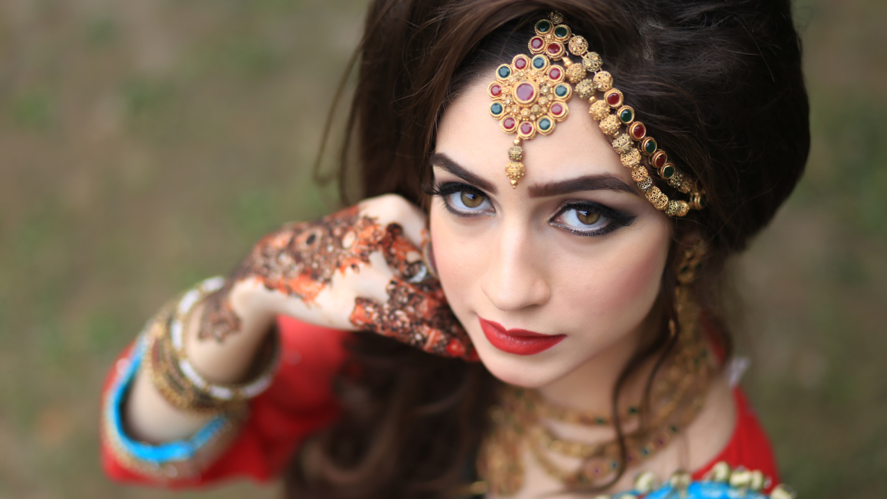 Красивая кареглазая девушка в индийском костюме с рисунками на руках 