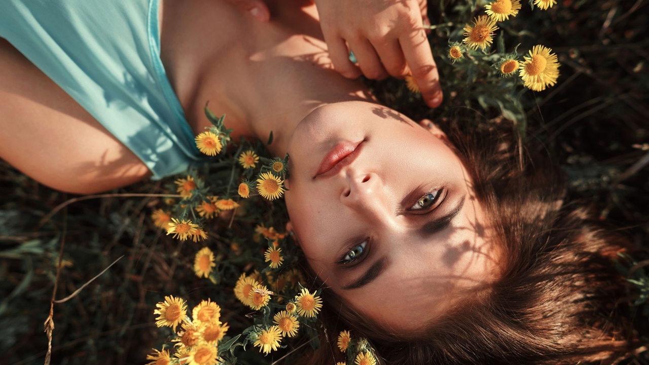 Красивая шатенка лежит на земле с желтыми цветами