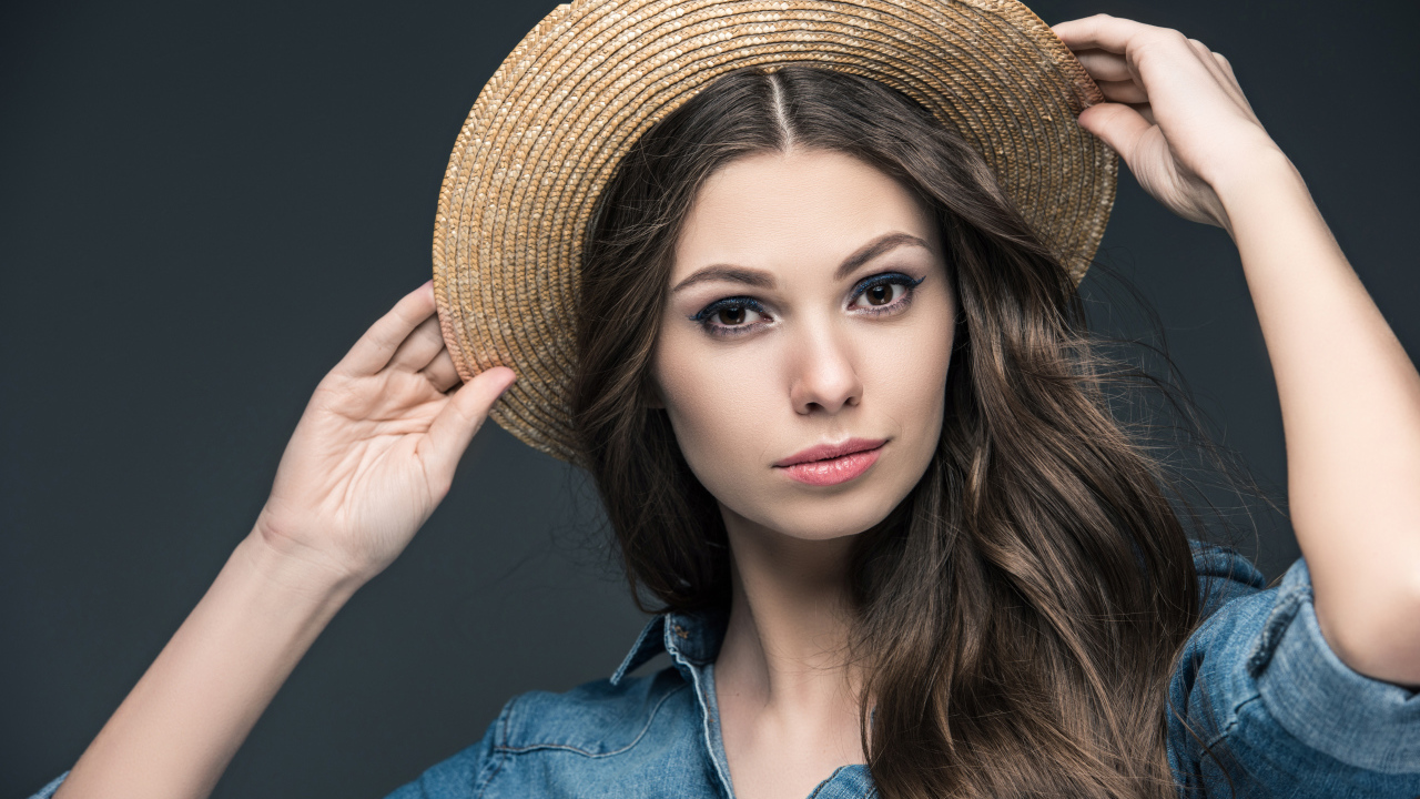 Красивая девушка в соломенной шляпе на сером фоне