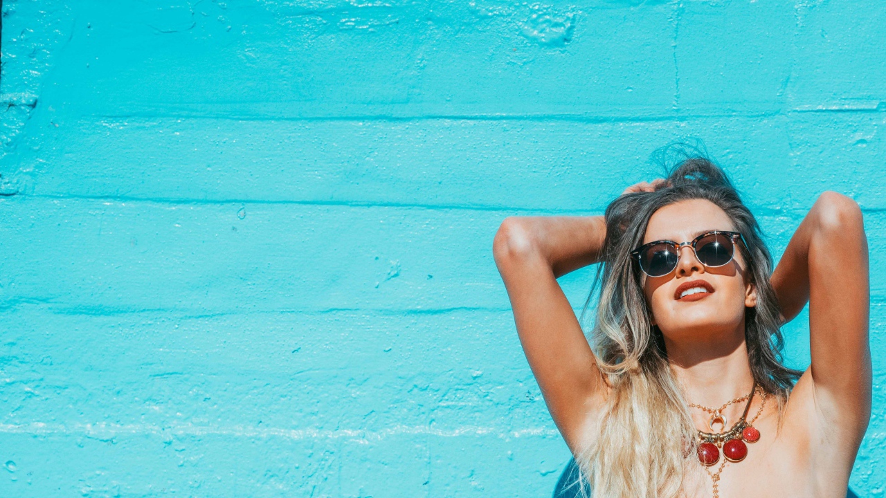 Красивая девушка в солнечных очках загорает на солнце летом