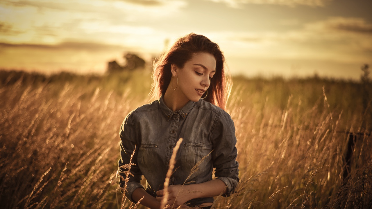 Красивая девушка на поле с колосками на фоне солнца