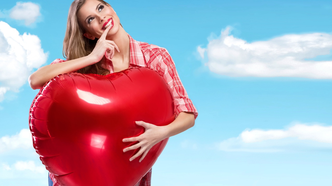 Красивая девушка с большим воздушным шаром в форме сердца на фоне неба