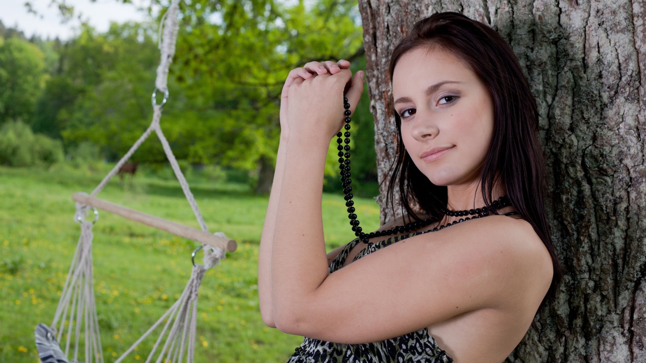 Красивая девушка с черными бусами под деревом