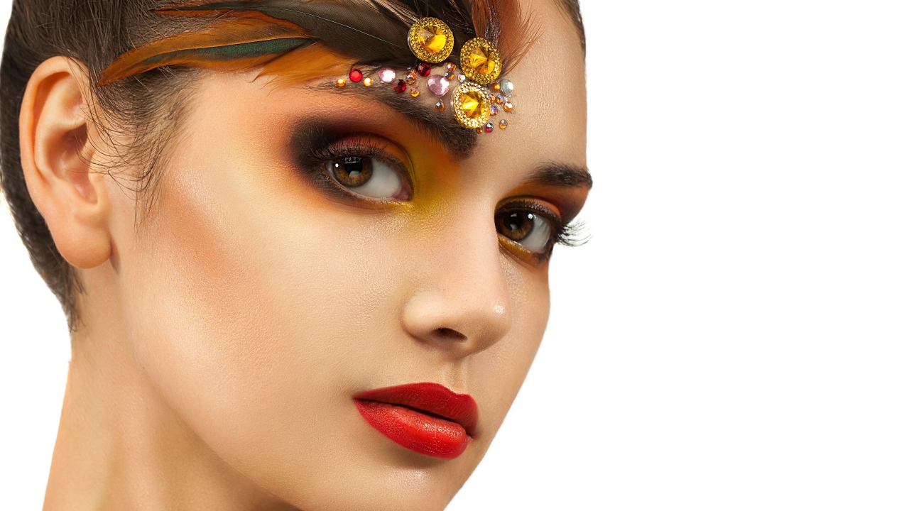 Красивая девушка с ярким макияжем и стразами на лице