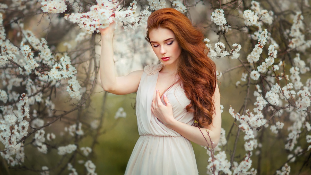 Красивая рыжеволосая девушка у цветущего дерева абрикоса 