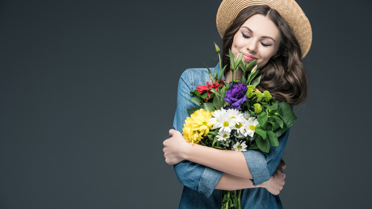 Красивая улыбающаяся девушка в шляпе с букетом цветов