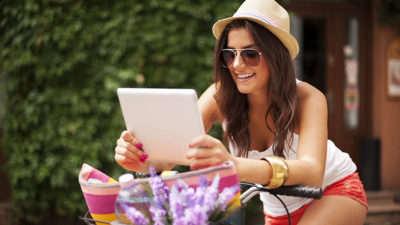 Красивая улыбающаяся девушка в шляпе с планшетом