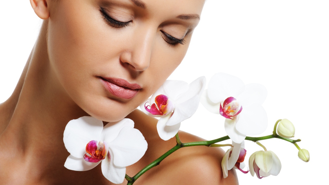 Красивая нежная девушка с цветами орхидеи на белом фоне