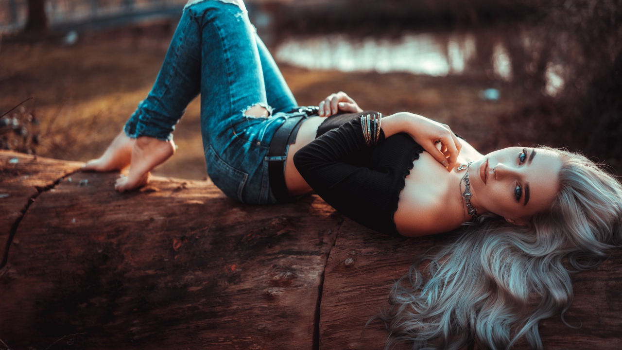 Красивая молодая блондинка лежит на сухом дереве