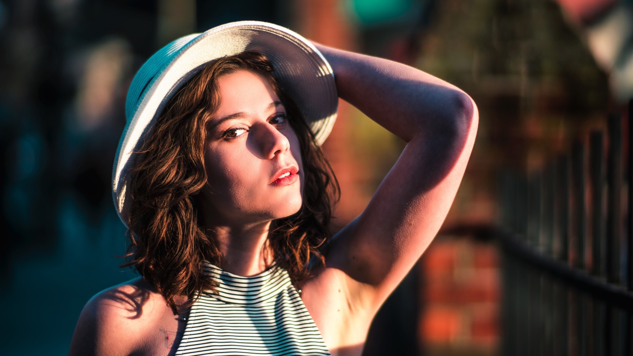 Красивая молодая девушка в белой шляпе в свете солнца