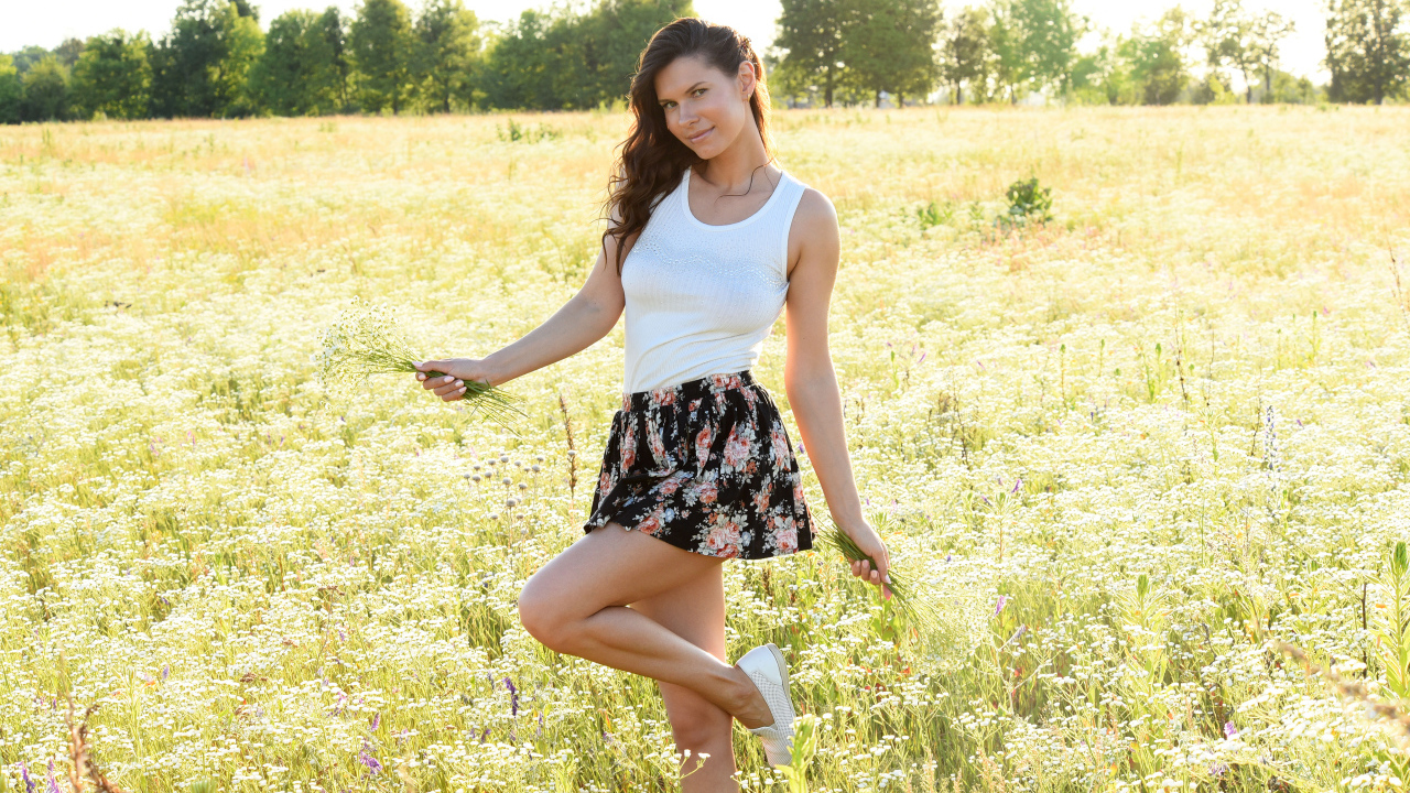 Красивая молодая девушка на поле с белыми ромашками