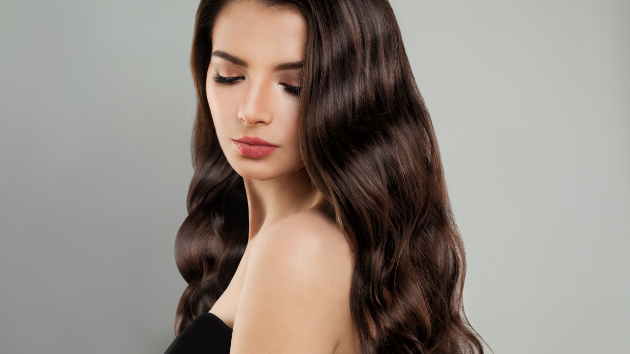 Красивая молодая длинноволосая девушка брюнетка на сером фоне