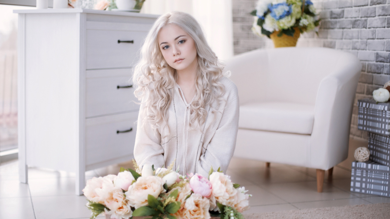 Девушка блондинка с пионами сидит в комнате