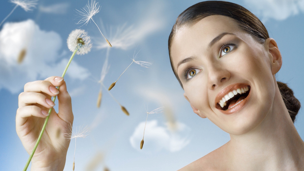 Счастливая девушка с одуванчиком в руке 