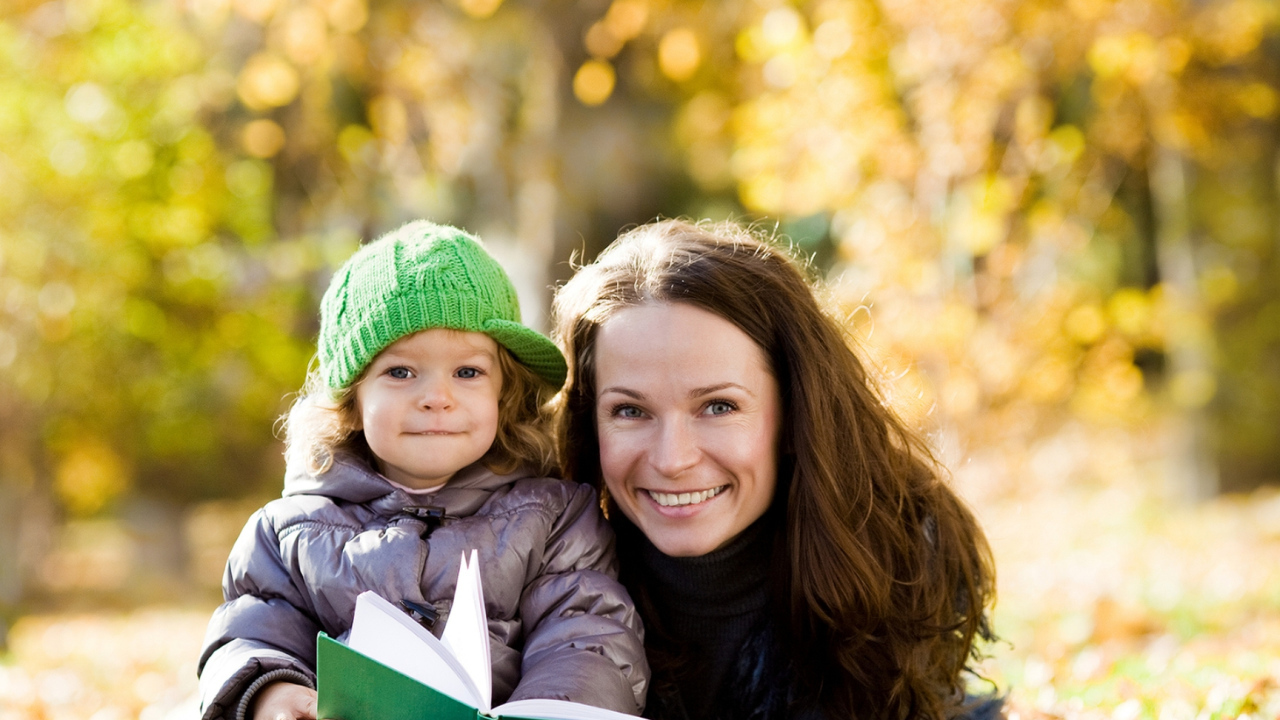 Улыбающаяся девушка с девочкой читают книгу