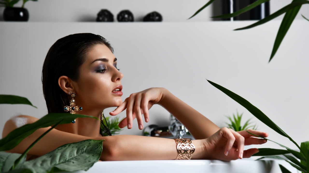 Девушка в дорогих украшения лежит в ванной