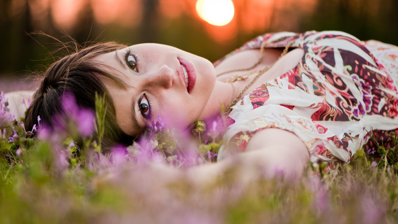 Молодая кареглазая девушка лежит на траве