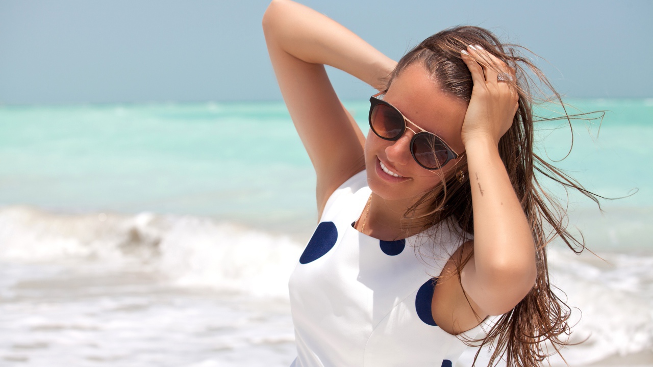 Молодая шатенка в солнечных очках у моря