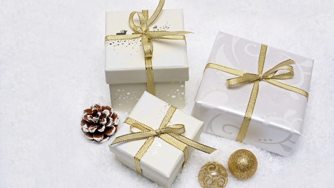 Три коробки с подарками с золотистыми бантами из ленты 