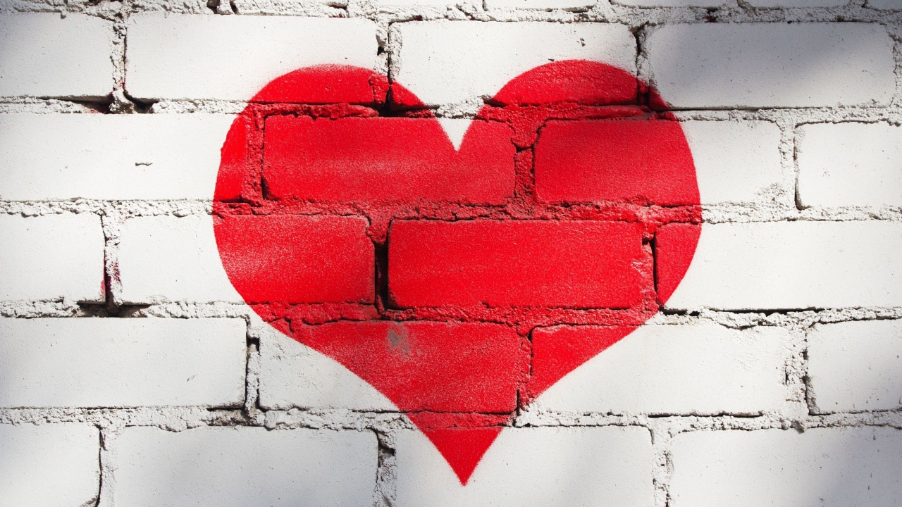 Большое красное сердце нарисовано на кирпичной стене