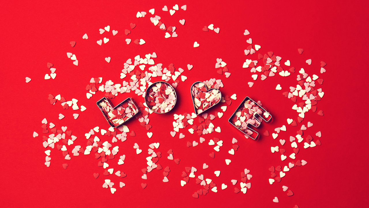 Надпись любовь из маленьких  сердечек на красном фоне