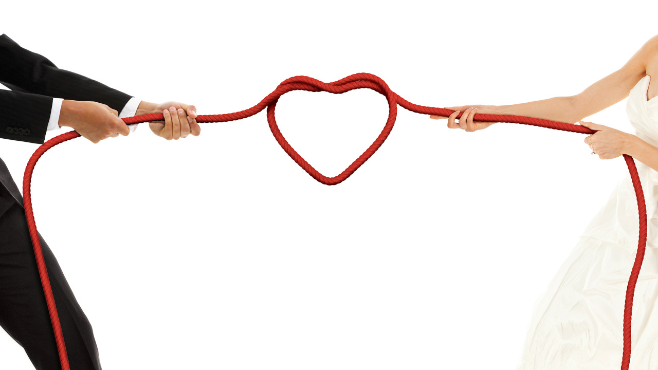 Newlyweds pull a rope with a heart on a white background