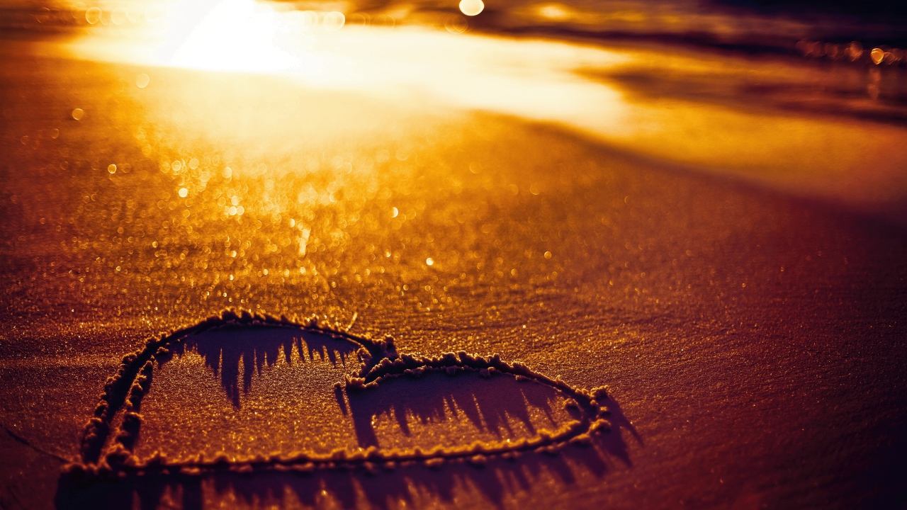 Нарисованное сердце на песке в лучах солнца