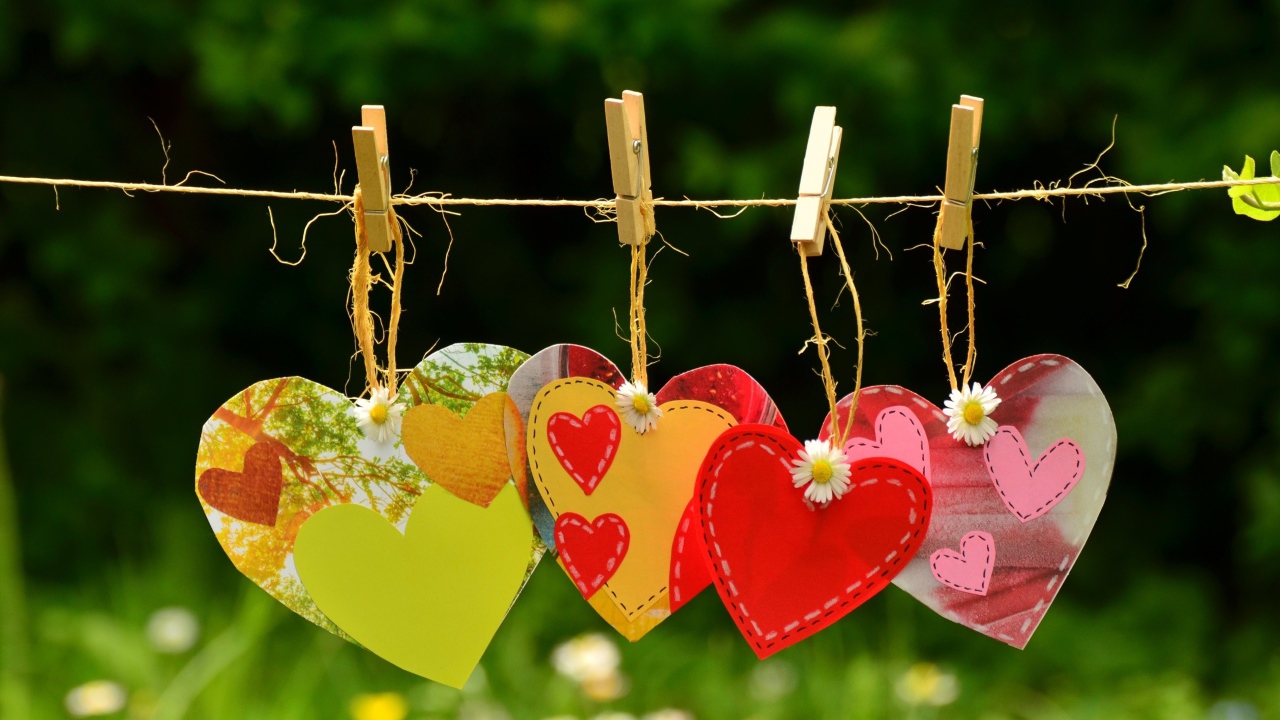 Бумажные сердечки висят на веревке на прищепках